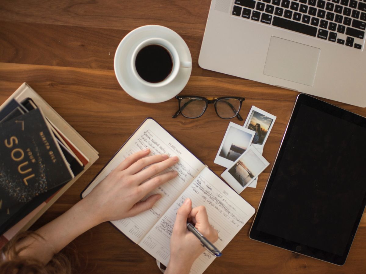 Someone writing in a notebook on a desk.