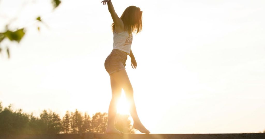 Woman balancing on a wooden plank outside